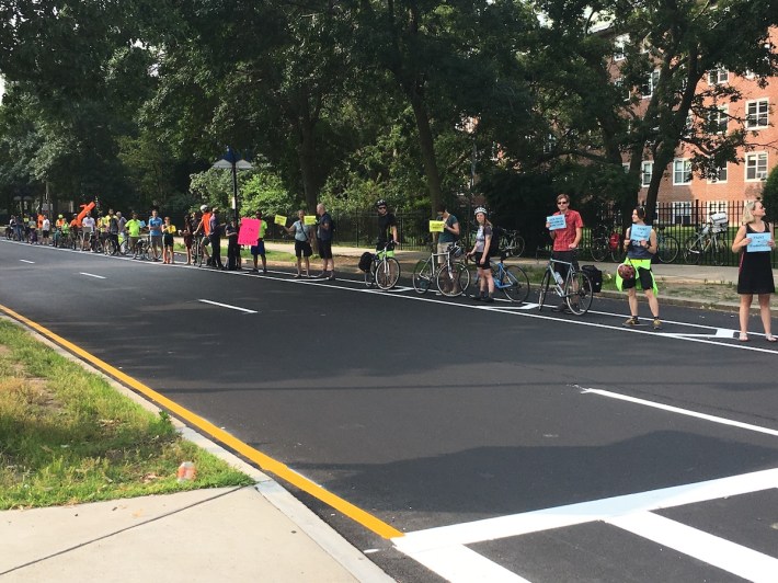 The Department of Conservation and Recreation (DCR) has painted new bike lanes on Fenway south of Brookline Avenue. The lanes have been criticized for their lack of physical protection, and for their poor design at intersections. During the morning rush hour on July 11, 2019, dozens of safety advocates lined the new bike lanes to create a "people-protected" barrier, holding signs that read "Paint ≠ Protection" and "DCR, keep me safe on your roads."