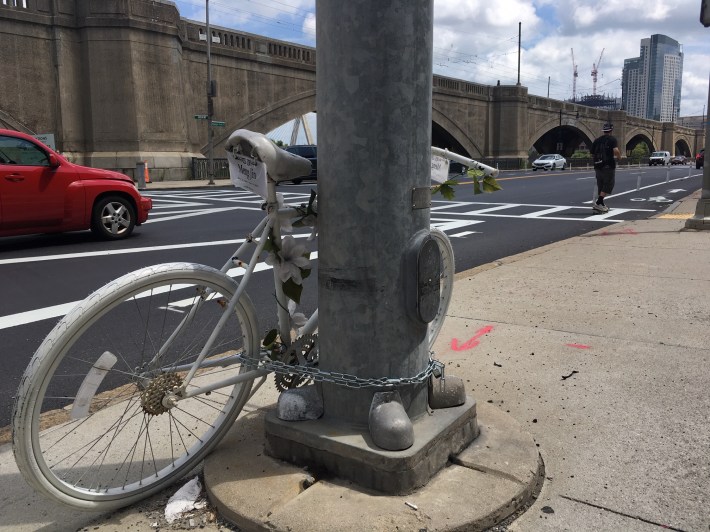 A ghost bike memorializes Meng Jin, a Boston University graduate student who was killed by a truck driver at the Museum Way/Charles River Dam Road intersection in February 2018.
