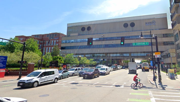 Massachusetts Avenue passes under the Boston Medical Center near Harrison Street in this 2019 Google Street View image. The City of Boston is planning a capital project that would provide a protected bikeway on this section of Mass. Ave., between Harrison Ave. and Melnea Cass Blvd.