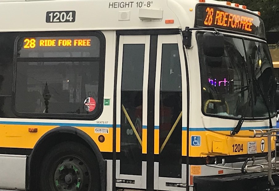 A route 28 bus advertising the fare-free pilot passes through Grove Hall on Blue Hill Avenue on October 5, 2021.