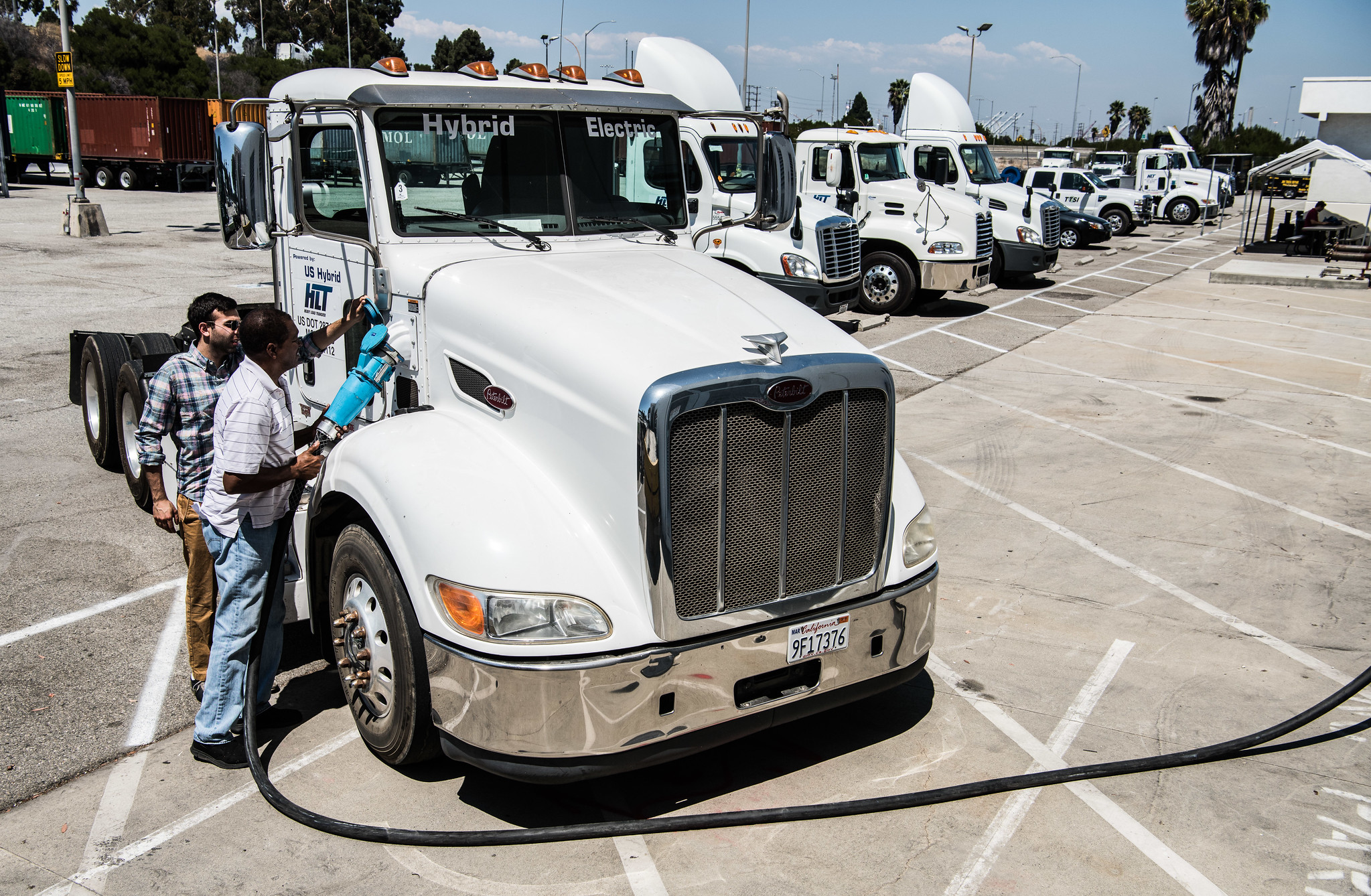 Workers plug in a hybrid-electric truck at the Long Beach Port in California