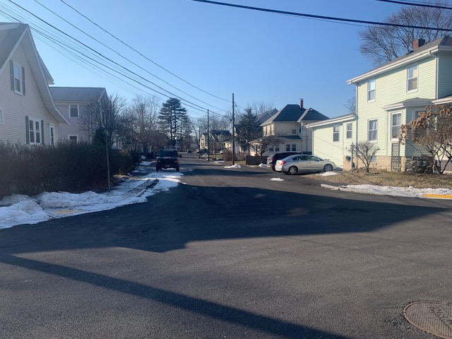 A photograph of Garfield Street in Natick after a recent repaving project. Both the sidewalks and the street were resurfaced in asphalt, making it extremely difficult to distinguish where the sidewalk is.