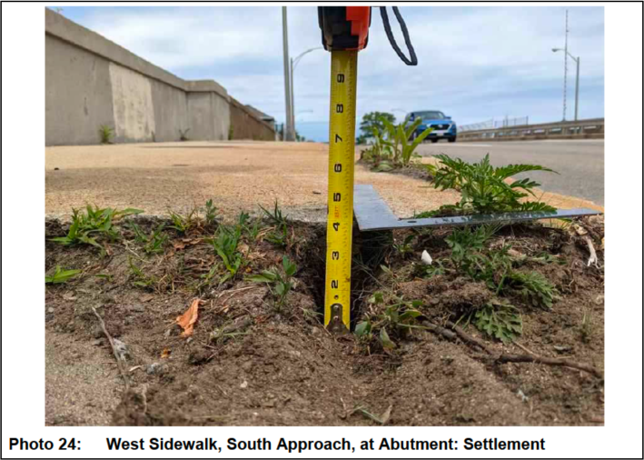 A photograph from MassDOT's 2021 inspection report illustrating a 4-inch gap from sidewalk settlement on the approach to the Beades Bridge in Dorchester.