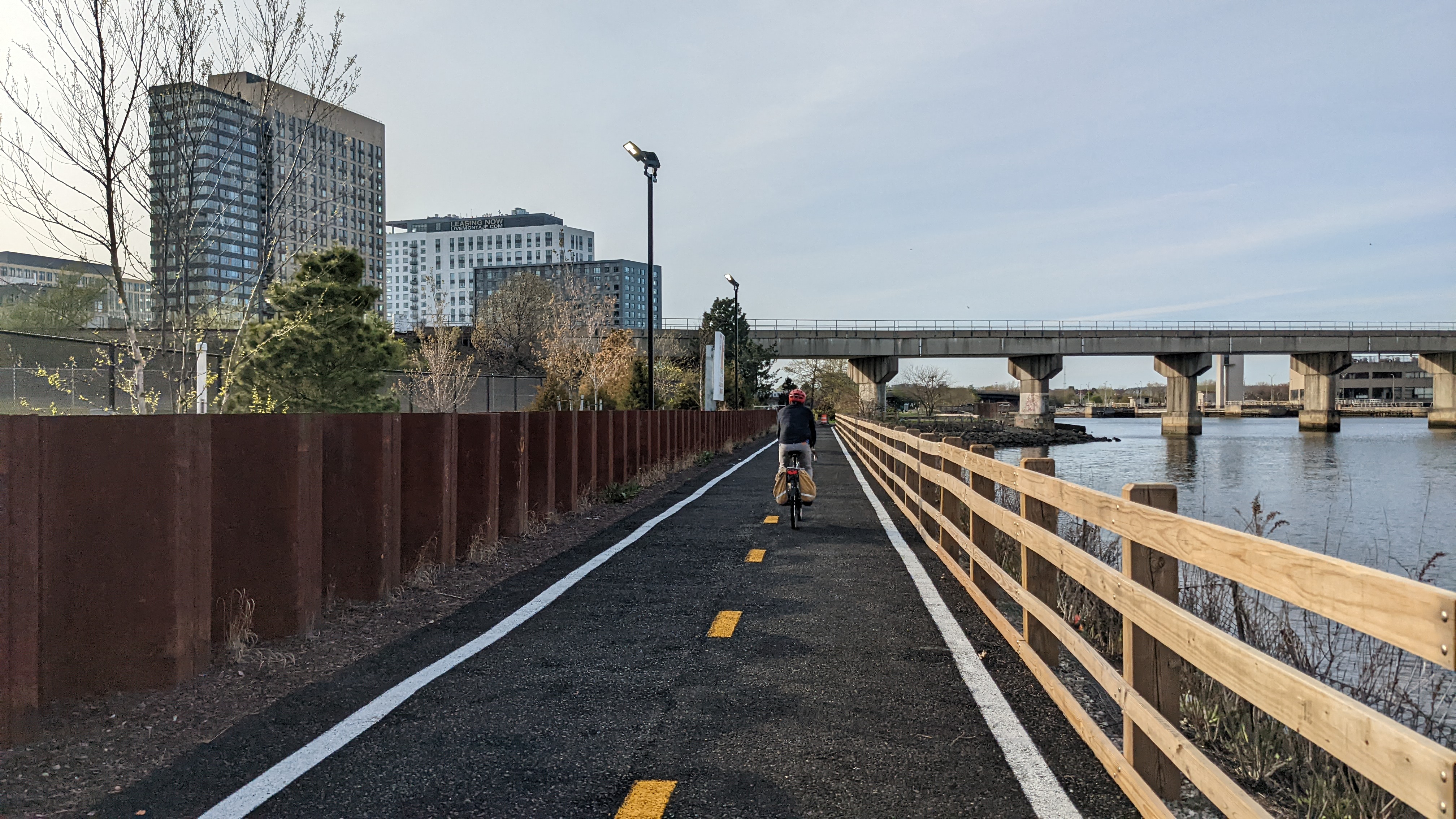 StreetsblogMASS editor Christian MilNeil rides along the new Charlestown Seawall trail towards Assembly Square (whose towers are visible in the background at left). The Mystic River is on the right.