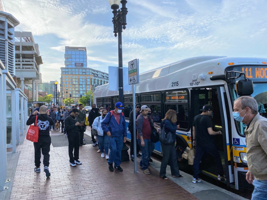 A long line of riders wait to board the 111 bus to Chelsea at the temporary Haymarket bus stop in downtown Boston.