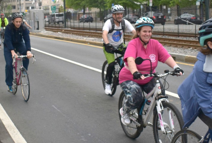 Four bicyclists ride in the middle of the rightmost lane of Commonwealth Avenue as part of a Bike to Work Day convoy.