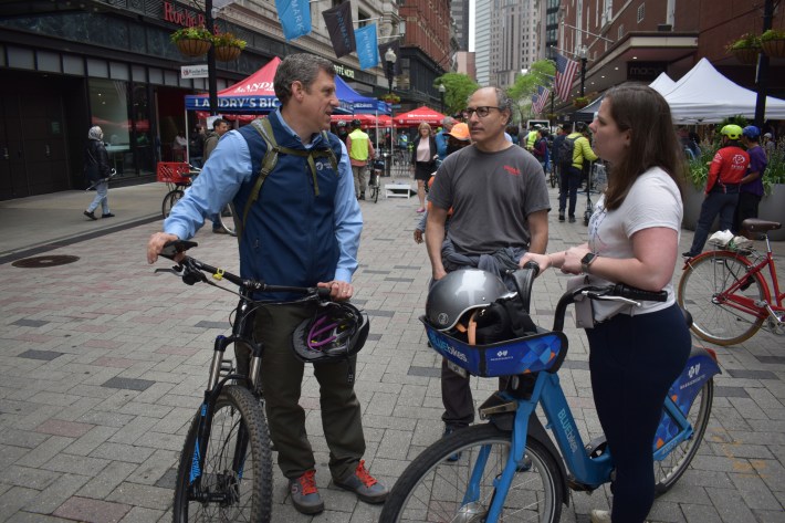 MassDOT Secretary Jamey Tesler, Jeff Rosenblum of Toole Design Group and Kirstie Hostetter, a transit planner with the City of Boston chat while holding their bikes in the middle of Summer Street in downtown Boston during the city's Bike to Work Day celebration.