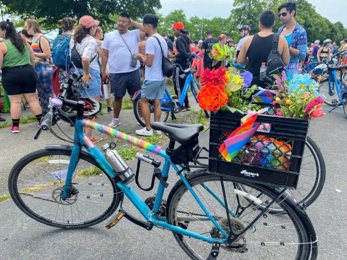 blue bicycle decorated with colorful flowers and pride flags