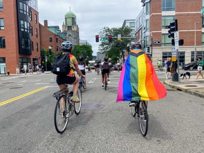 bicyclists cruising along West Broadway coming up on A Street with the pride flag blowing in the wind.