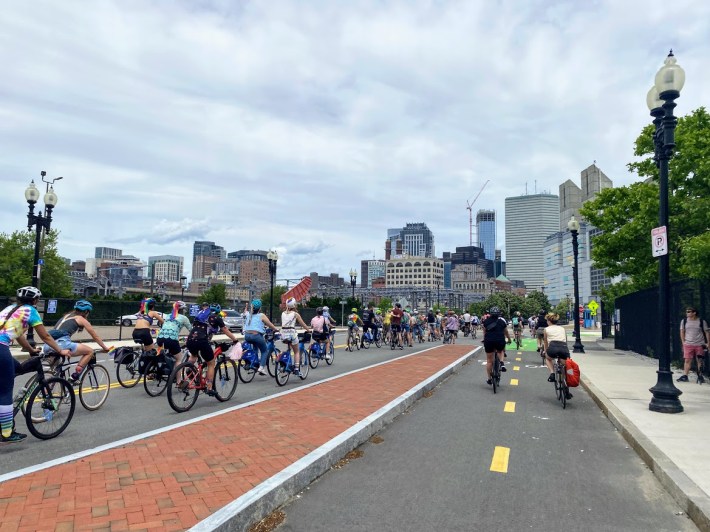 bike riders on dorchester ave with the boston skyline in the background