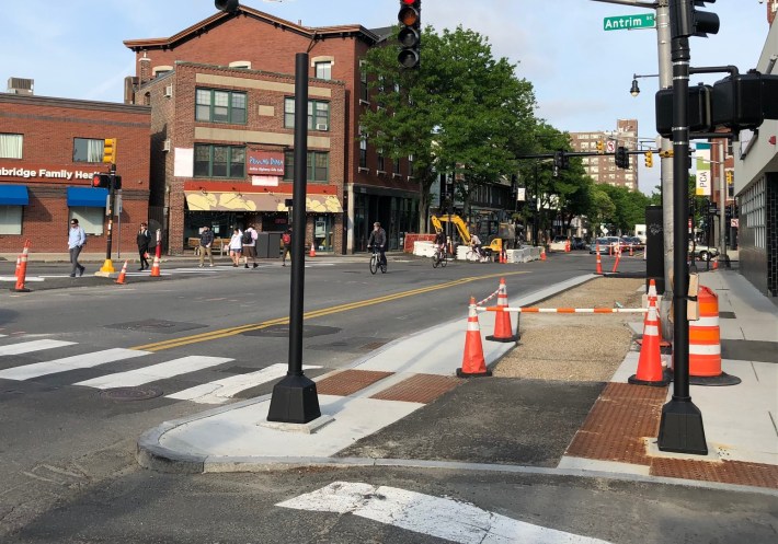 A protected bike lane and new sidewalk under construction on the south side of Cambridge Street in Inman Square.