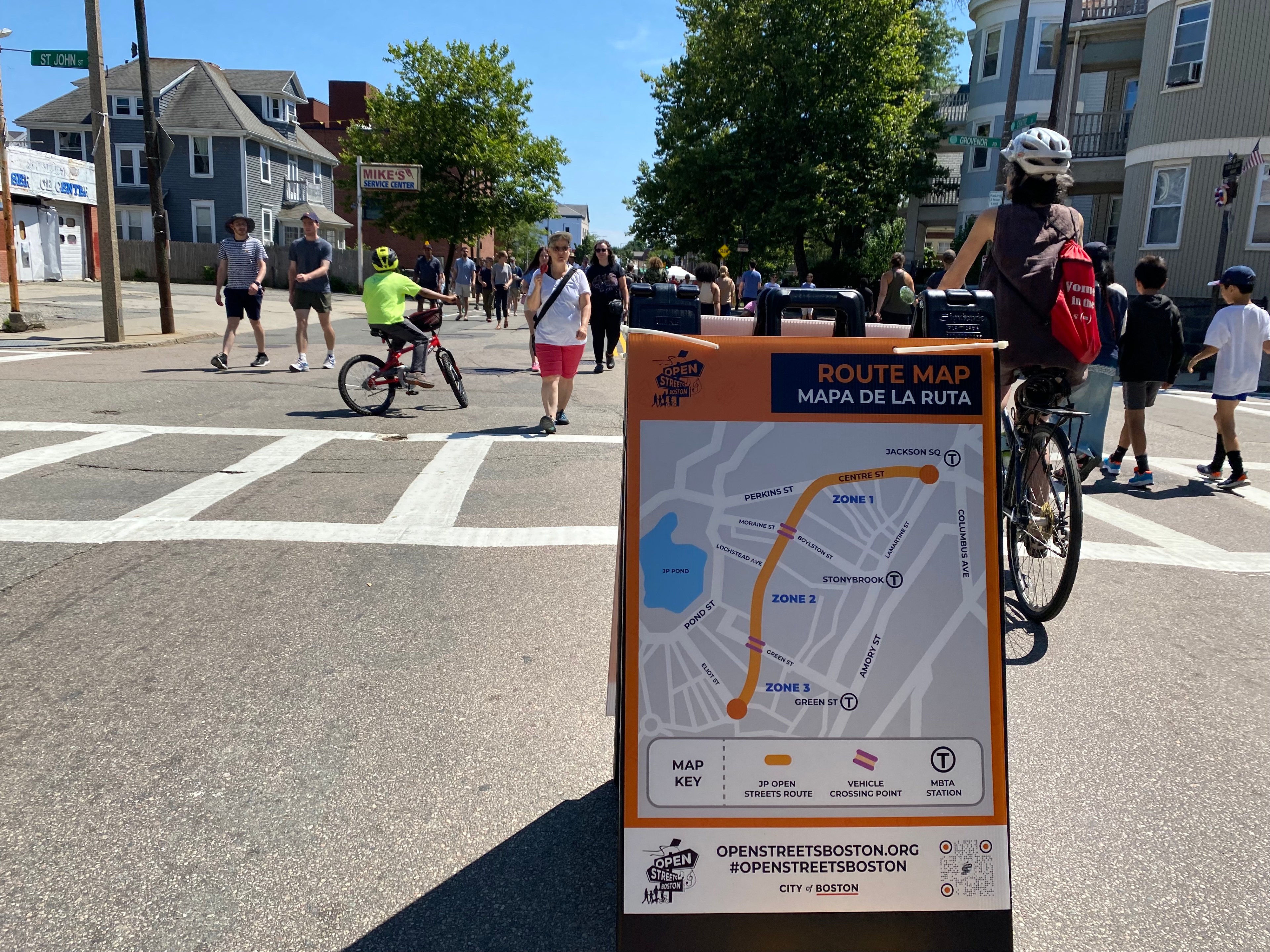 Crowds walk and roll past a map of Sunday's Open Streets event in Jamaica Plain.