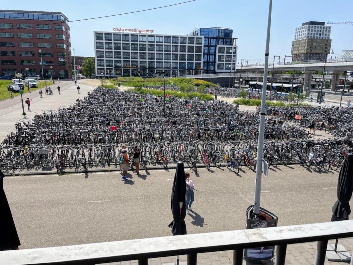 Rows of bike parking next to a bus stop and a raised railway line near a meeting center in Amsterdam. Photo by Lisa Jacobson.