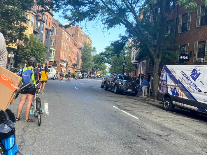 A portion of the people-protected bike lane next to a parking lane on Charles Street at 9:00am. Currently this street has parking on both sides with three one way travel lanes running down the middle.
