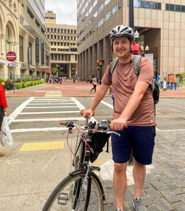 Roslindale resident Andrew Murray poses with his bike in downtown Boston with City Hall in the background – the final destination of Thursday morning’s bike ride with Mayor Michelle Wu. Over 50 community members rode their bikes together for nearly 7 miles from Roslindale.