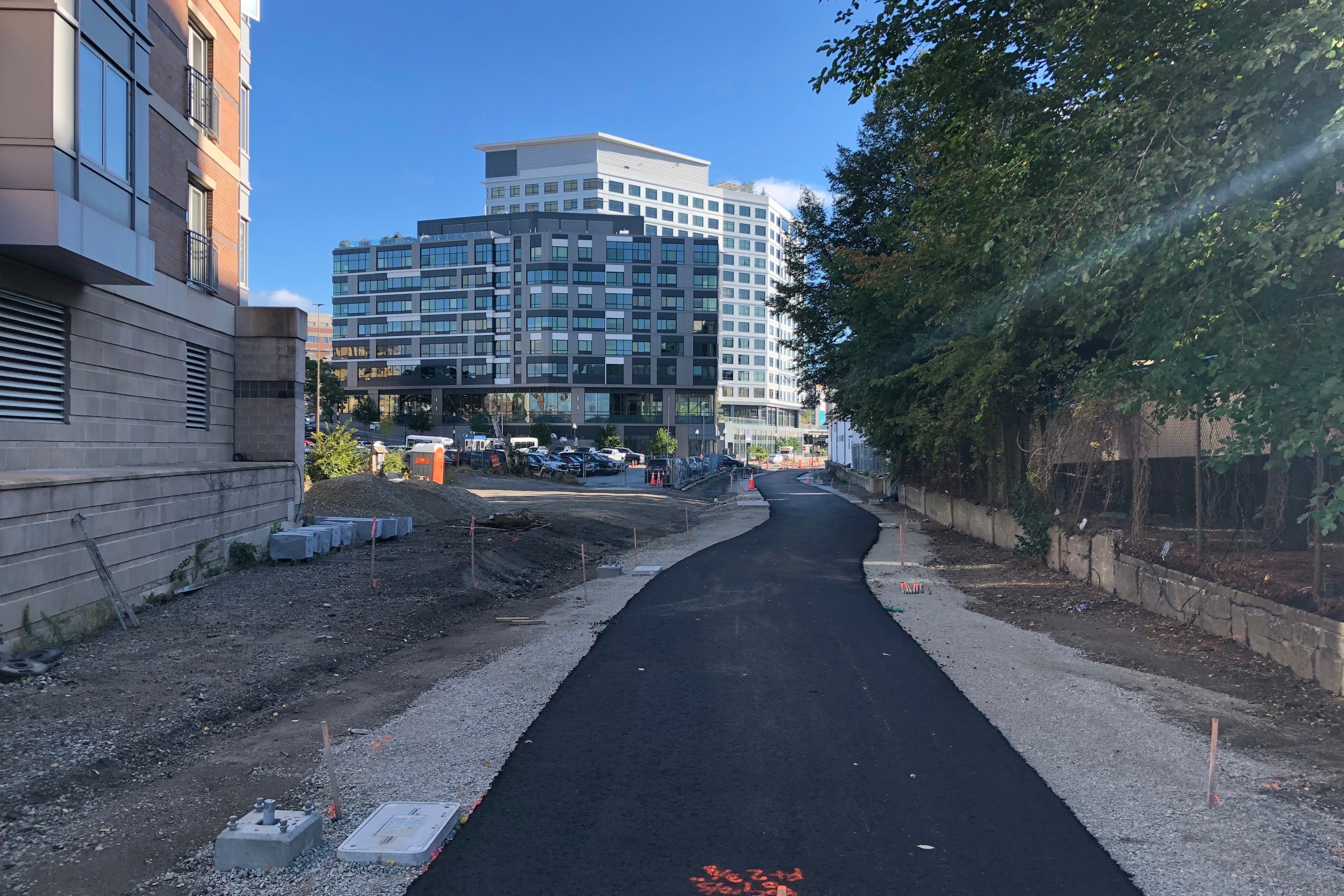 Fresh pavement on an under-construction bike path. In the distance are two new tall buildings near Kenmore Square.