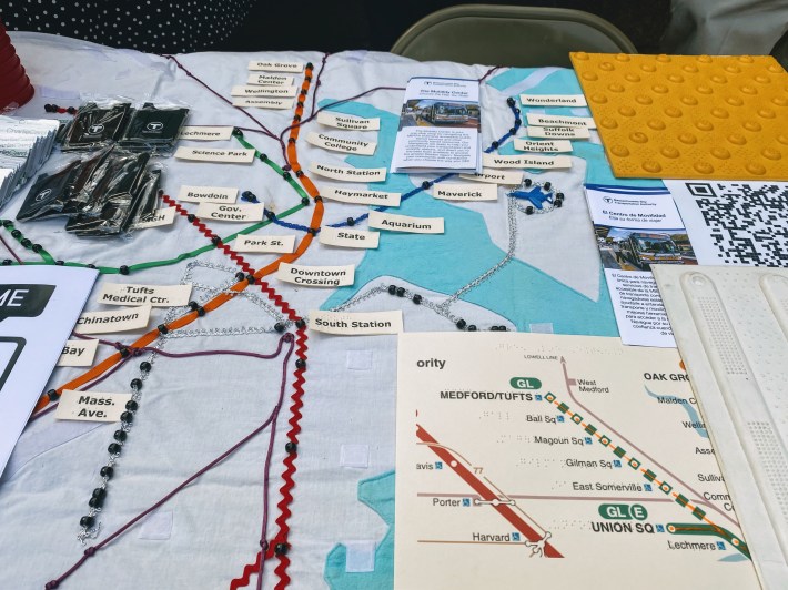 a cloth MBTA system maps with red, orange, green, purple and gray ribbons representing different train lines