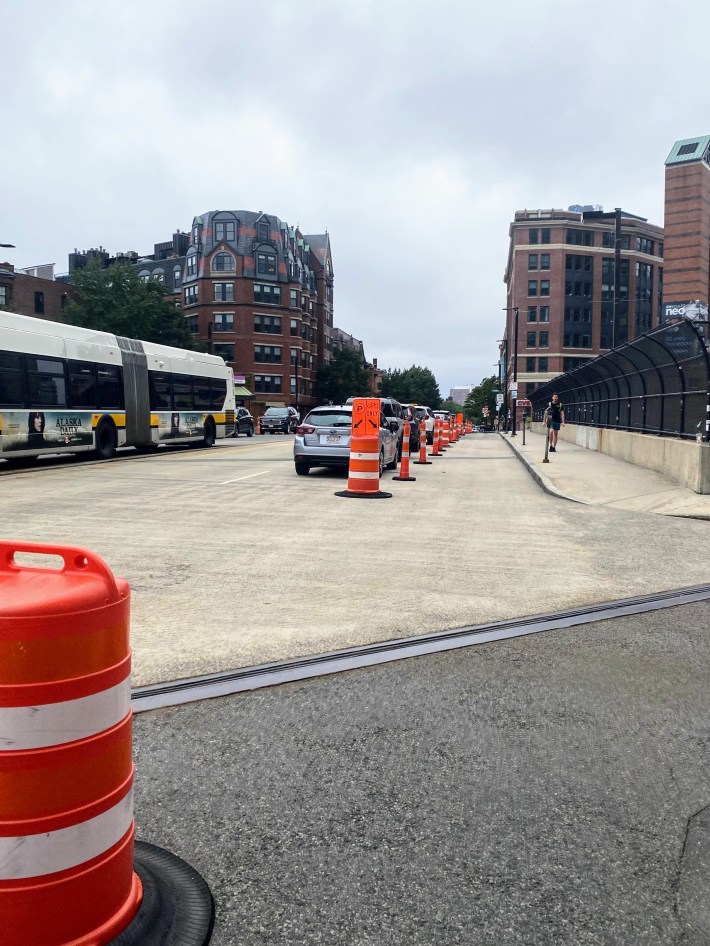 Pedestrian walks next to the pop-up bike lane along Columbus Avenue in Back Bay yesterday afternoon.