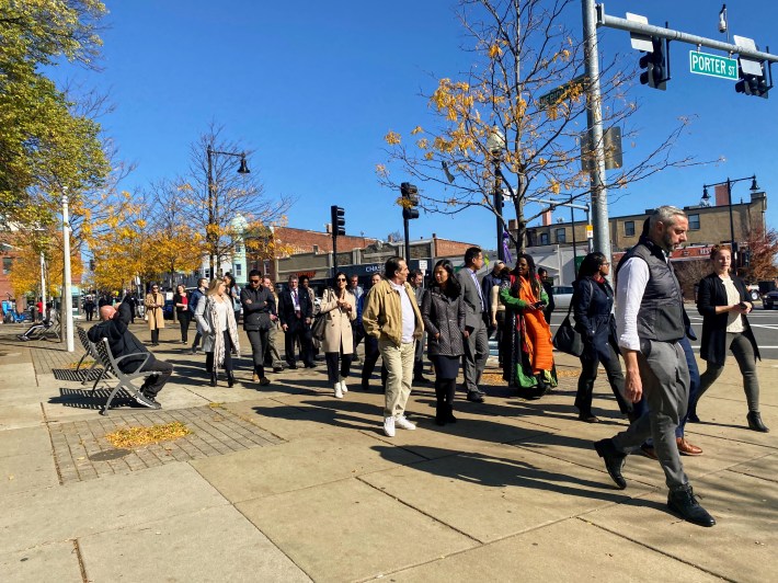 a group of people walk along a guided tour of Central Square Park.