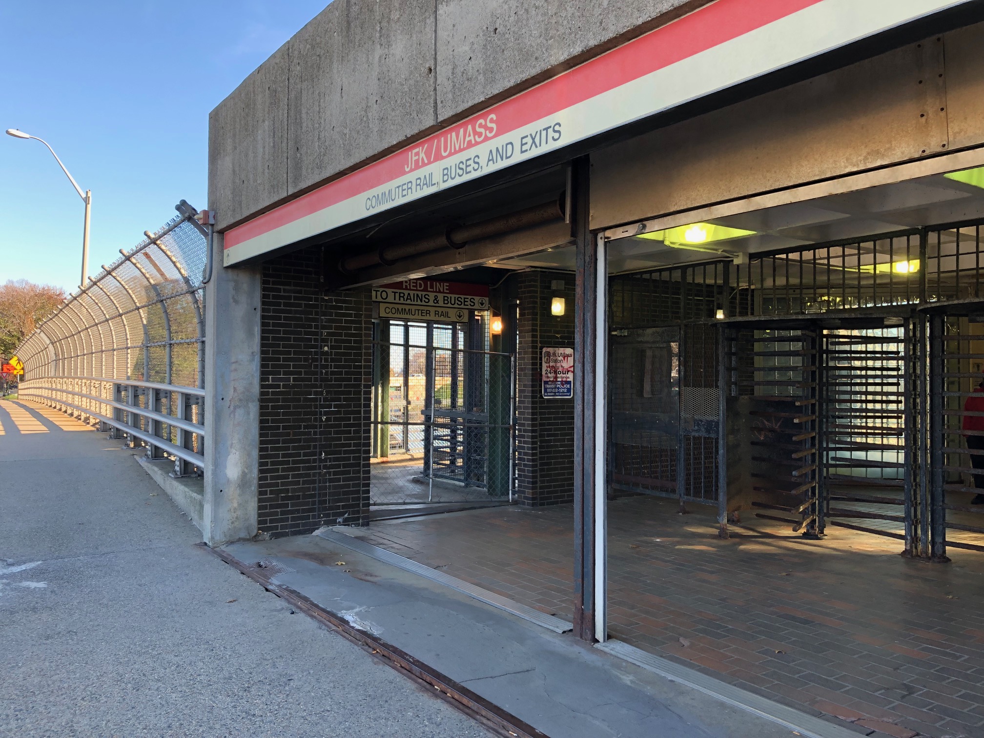 A chain-link fence blocks the entrance to the JFK/UMass Red Line station.