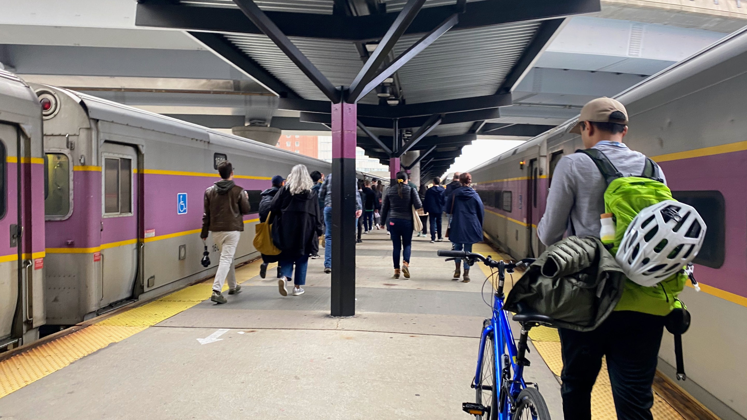 Group of people walking toward the train doors on the North Station platform,