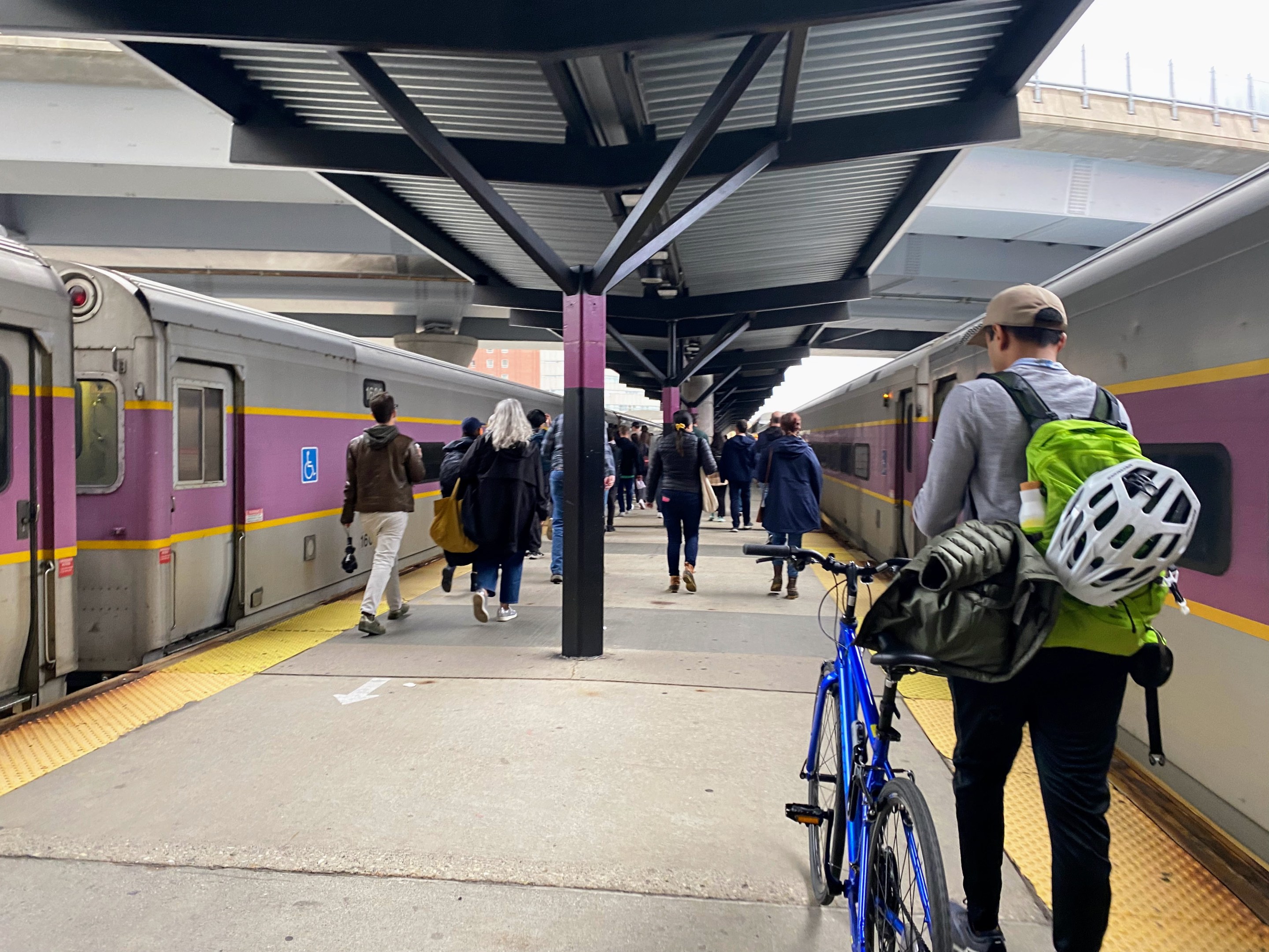 Group of people walking toward the train doors on the North Station platform,