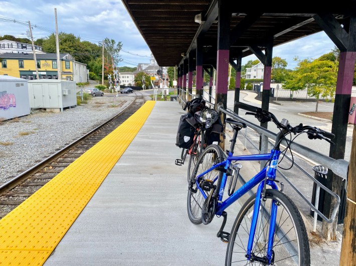 a blue and pink bike leaning against the metal bars on the commuter rail platform in Ipswich.