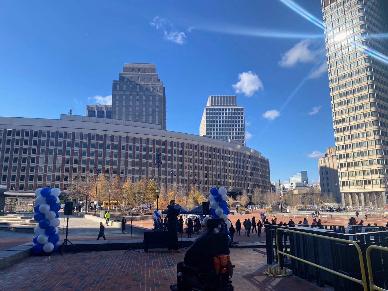 A person using a wheelchair overlooks the newly opened Boston City Hall Plaza under a bright blue winter sky.
