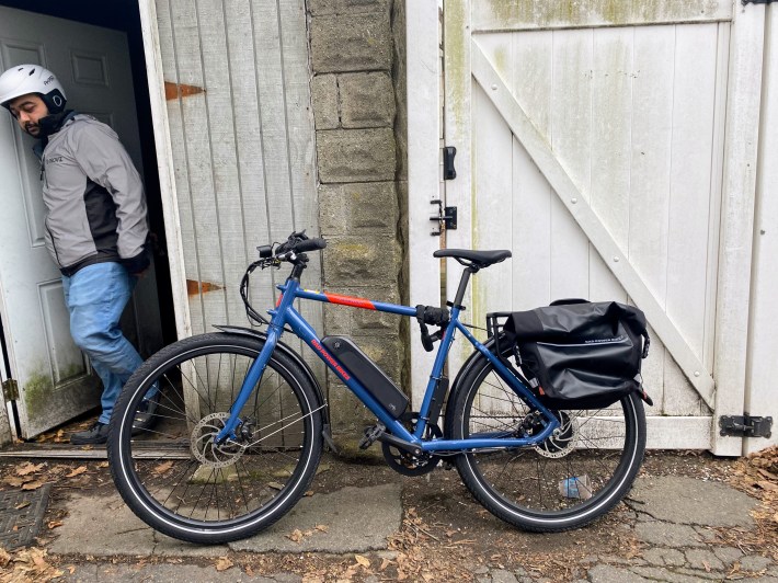 Deodhar's e-bike leans against the wall as he exits the storage shed.