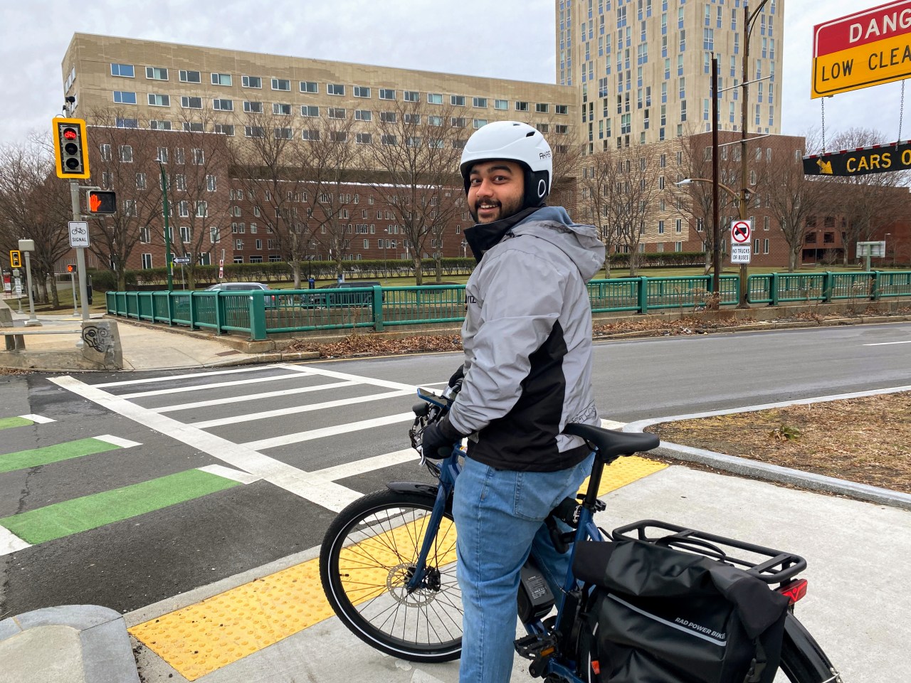 Aseem Deodhar smiles as he waits to cross the street on his e-bike.