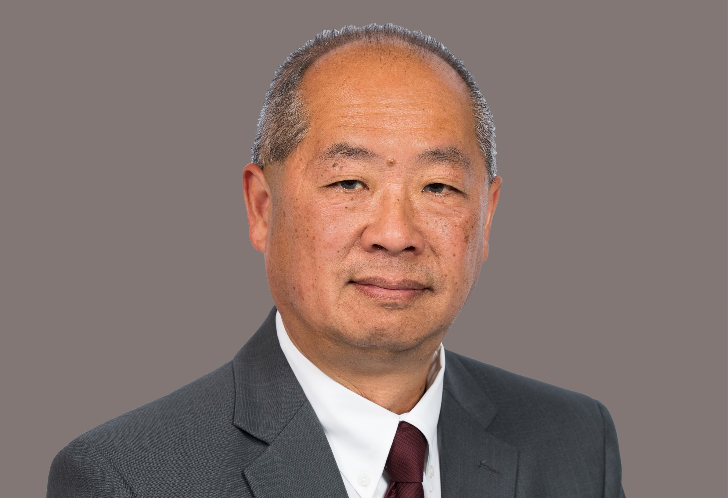 Phillip Eng headshot: a middle-aged man with close-cropped hair wearing a dark grey suit and red tie.