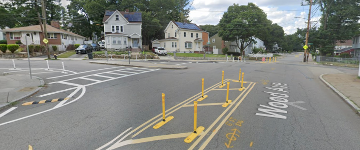The City of Boston recently installed new flexible-post bollards at several intersections along Wood Avenue in Hyde Park in an effort to slow down dangerous drivers. The bollards encourage slower speeds by forcing drivers to take turns at tighter angles through the neighborhood's unusually wide intersections, like this one at Wood Avenue and Tacoma Street. Courtesy of Google Street View.
