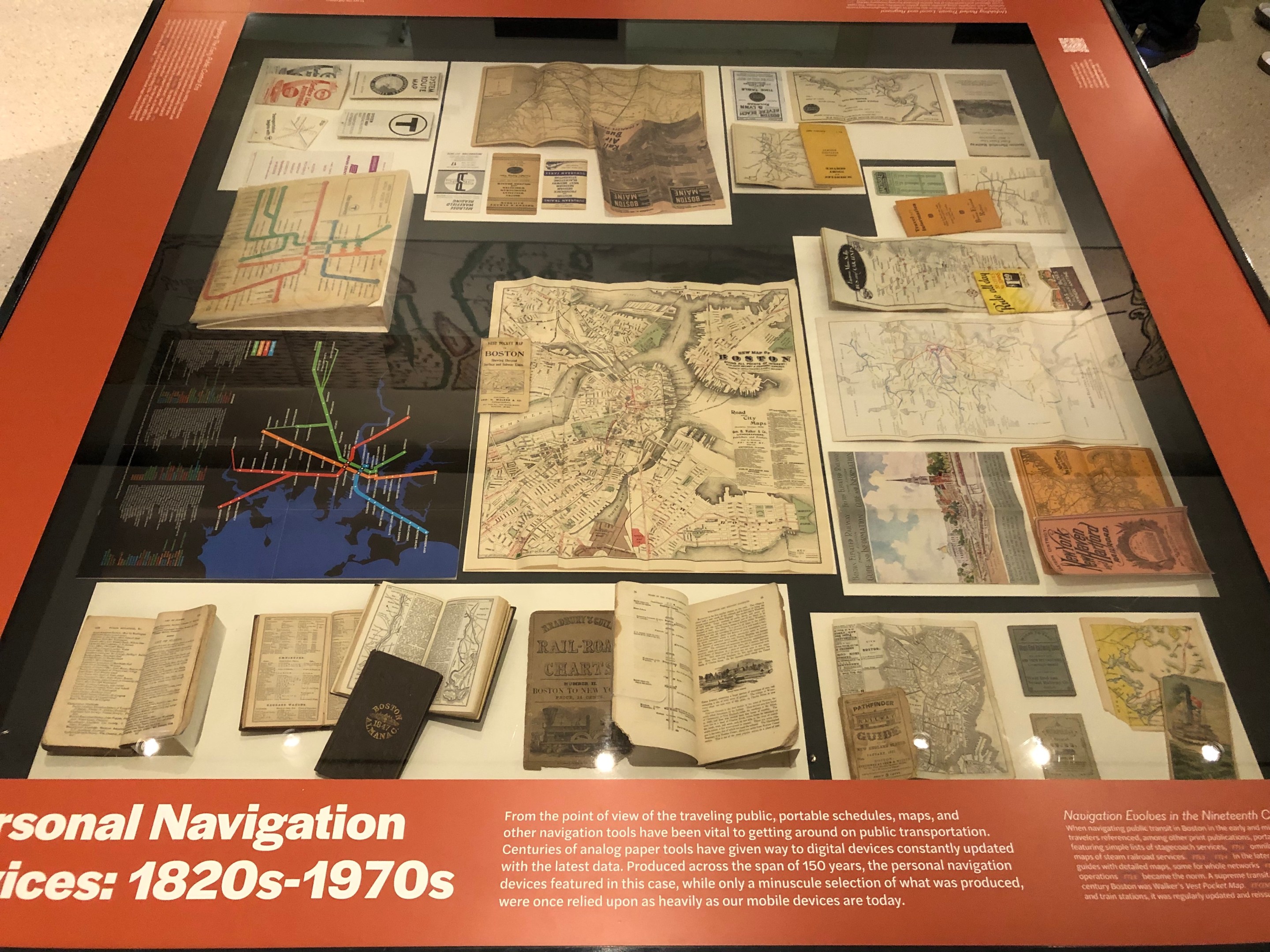 A display case of pocket-sized transit navigational guides, ranging from early railroad timetables to late-twentieth-century subway maps, from the Norman B. Leventhal Map & Education Center's exhibition "Getting Around Town: Four Centuries of Mapping Boston in Transit"