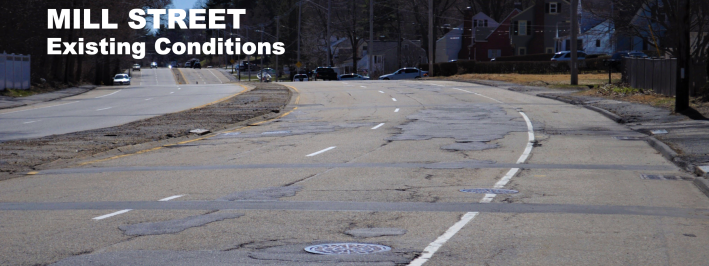 A four-lane highway with patched, cracked pavement, mostly empty of cars. 