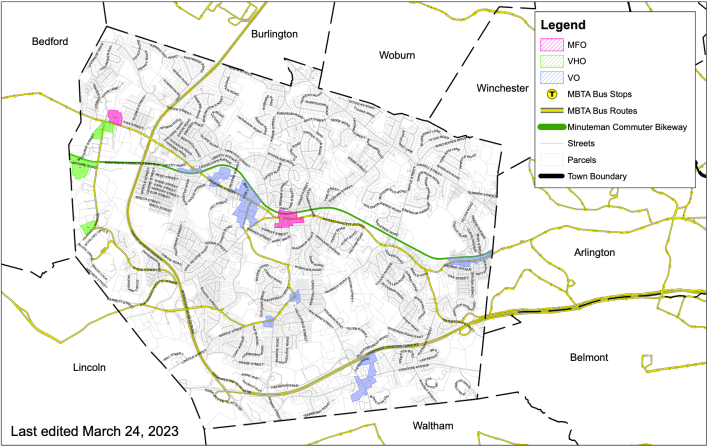 A zoning map of the Town of Lexington. A curved green line running roughly horizontally through the middle of the town map indicates the location of the Minuteman Commuter Bikeway. Interstate 95/Route 128 curves through the western part of the town in a yellow C-shaped line. Small colored blobs, mostly located along the Minuteman path, indicate new zoning districts where the town will allow multi-family apartment buildings.