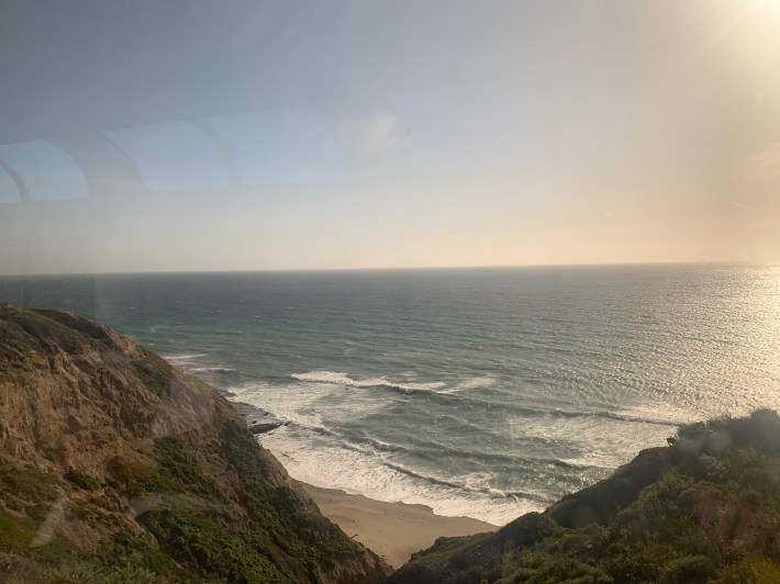 The sun beginning to set over the beach along the southern coast of California from the window of an Amtrak train