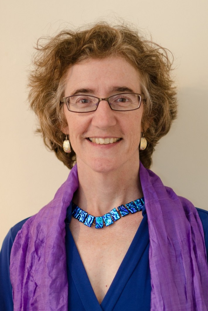 A woman with short wavy brown hair and eyeglasses.