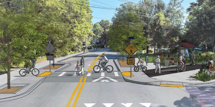 A rendering superimposed over a photograph of a street lined with trees. The rendering illustrates a drawn crosswalk on top of a speed hump with several people walking or biking through the crosswalk, and a drawing of a trail and trail kiosk leading into the trees at right.