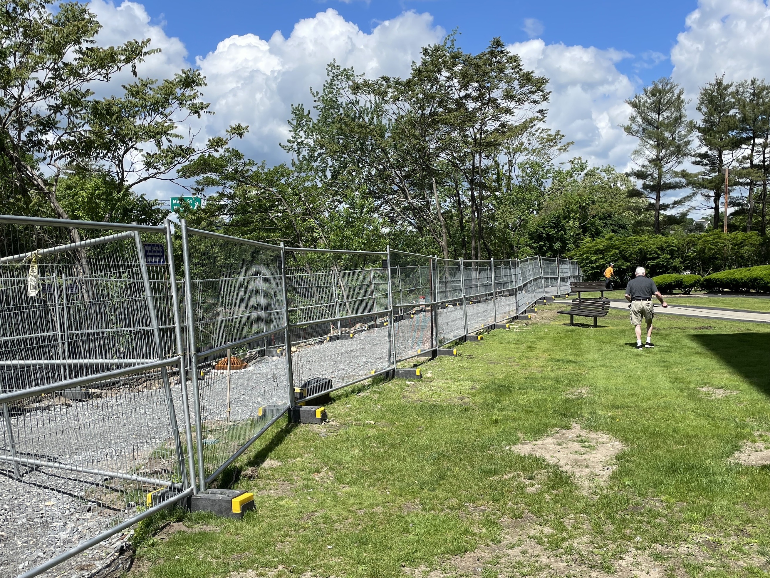 A gravel path under construction behind a metal fence next to a grassy lawn
