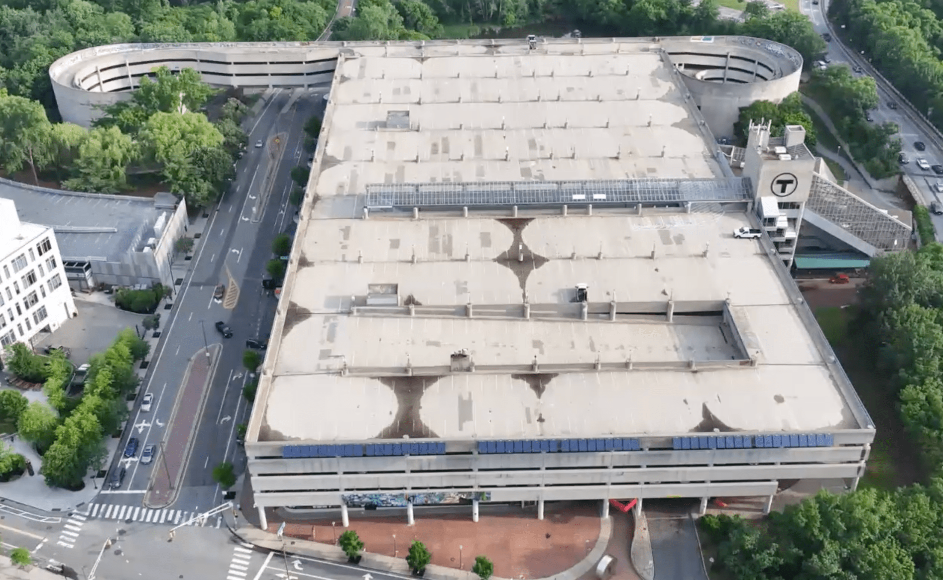 A drone's-eye view of the massive Alewife parking garage in Cambridge. The top level of the garage is roughly the size of 3.5 football fields, and is completely empty of any parked cars in the image.