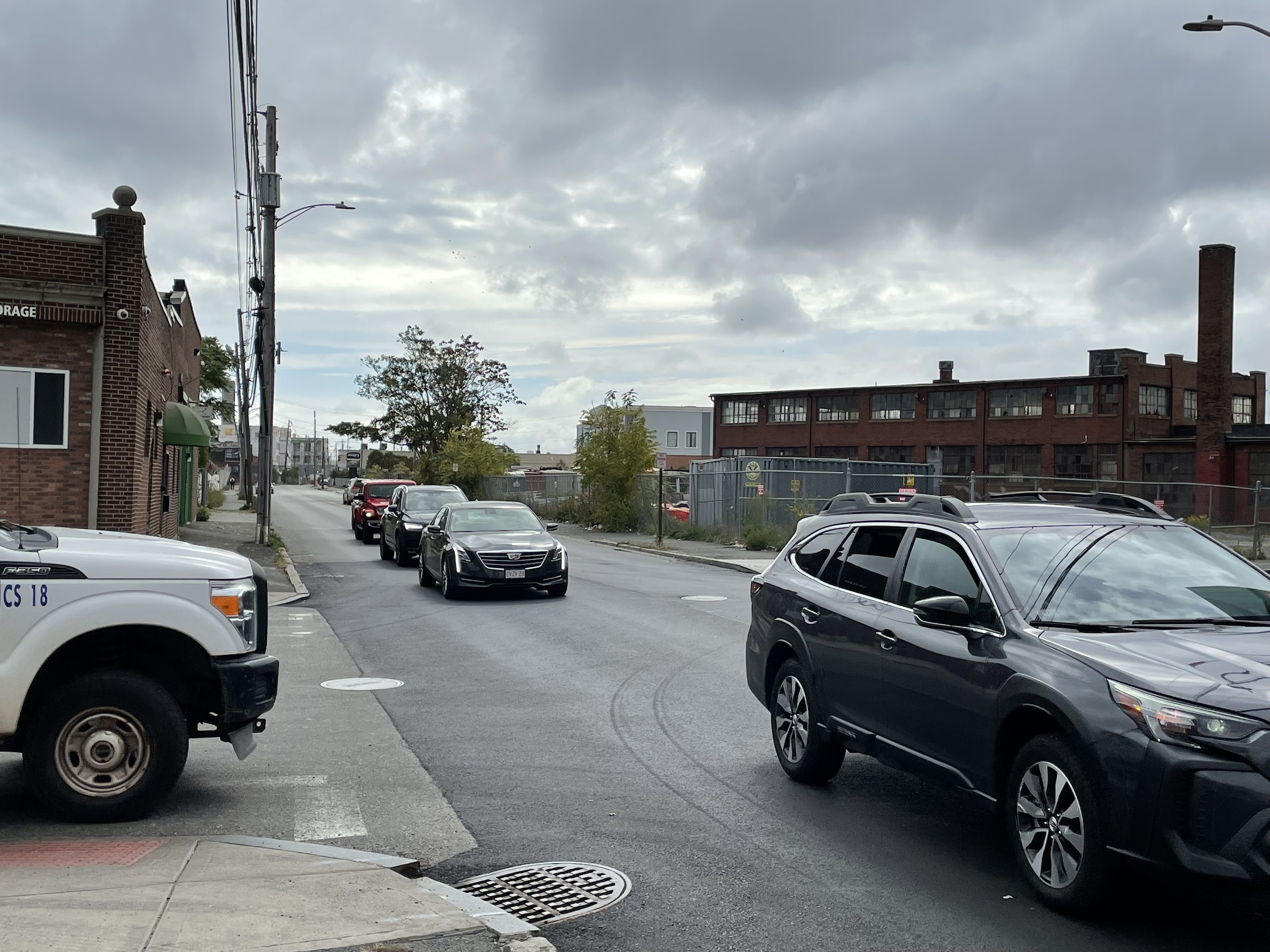 A relatively narrow 2-lane street running between two older brick industrial buildings.