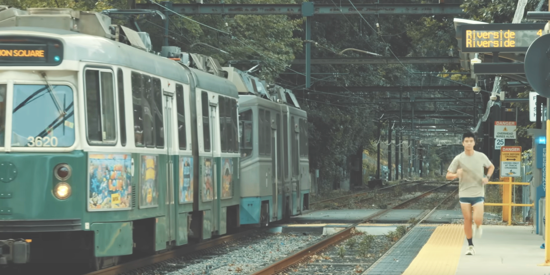 A man runs along a train platform next to a Green Line train.