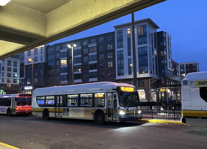 A yellow and white 104 Malden bus sitting outside of Malden station.