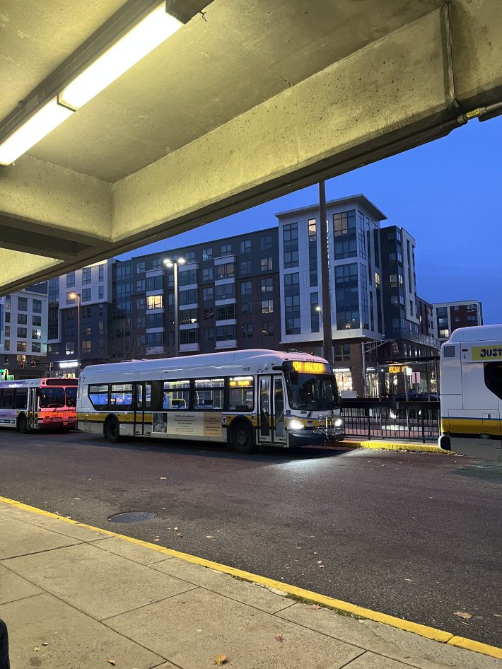 A yellow and white 104 Malden bus sitting outside of Malden station.