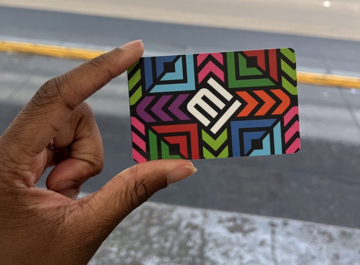 A close-up of Mexico City's metro card, which features a colorful grid of squares and diagonal lines surrounding the letters "MI" on a diagonal in the center of the card.