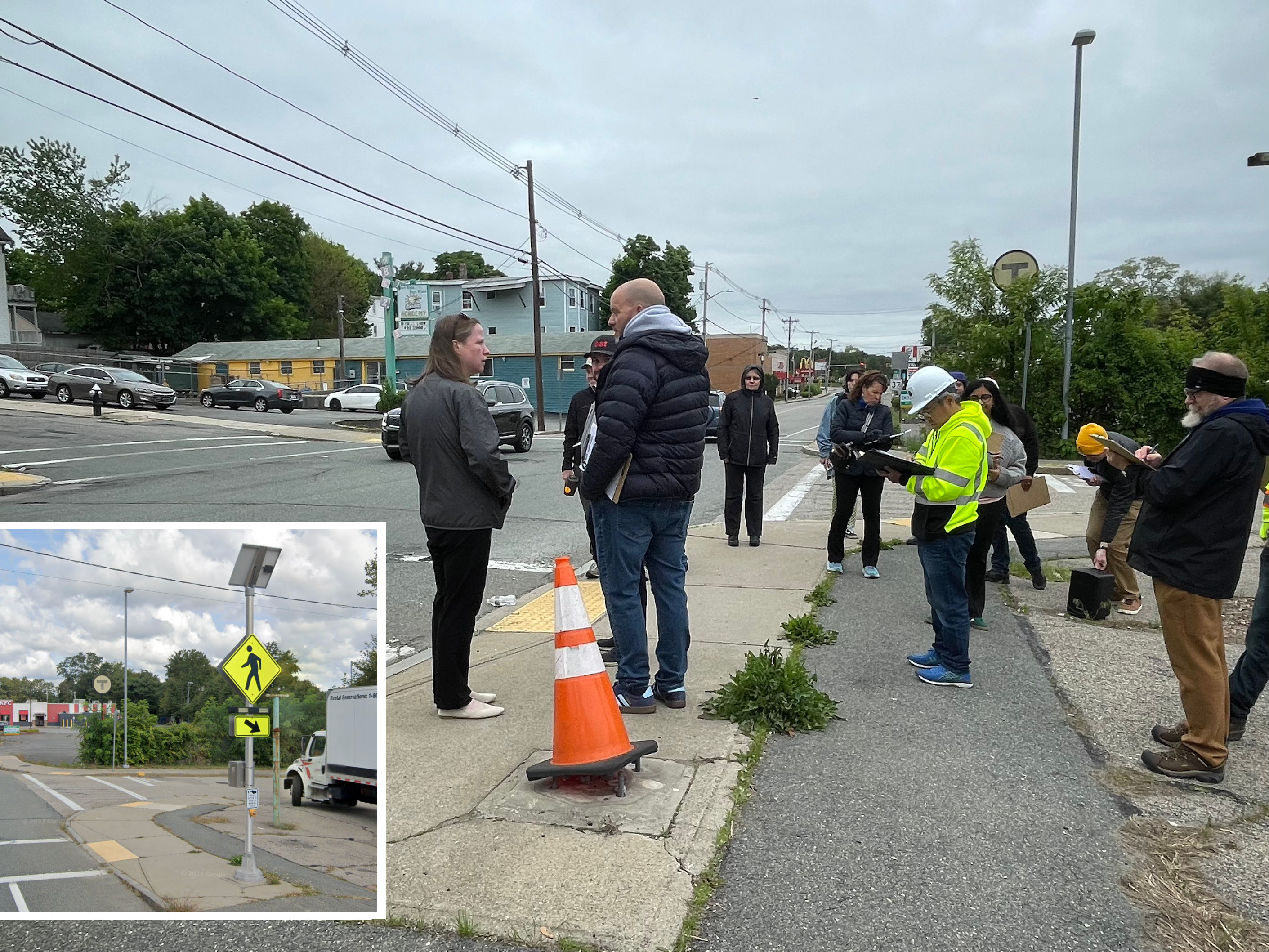 A small crowd of people in jackets gather on a poorly maintained sidewalk next to an orange traffic cone. An inset image shows the same corner from Google Street view, when a pedestrian crossing sign and set of flashing lights had been installed on the same pedestal where the cone is today.