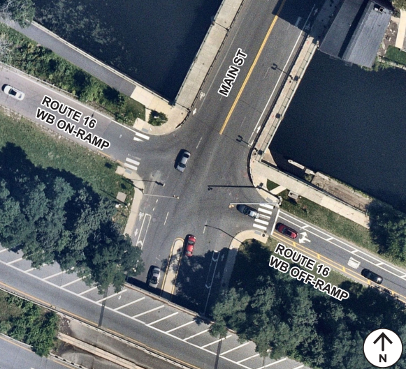 Overhead view of the intersection of Main Street, Mystic Avenue, and Union Street. Includes bus/bike lanes, crosswalks, turning lanes, commercial buildings, and parking lots.