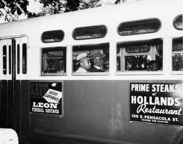 Black men in suits and hats sit on a bus in Tallahassee during a protest against segregated seating.