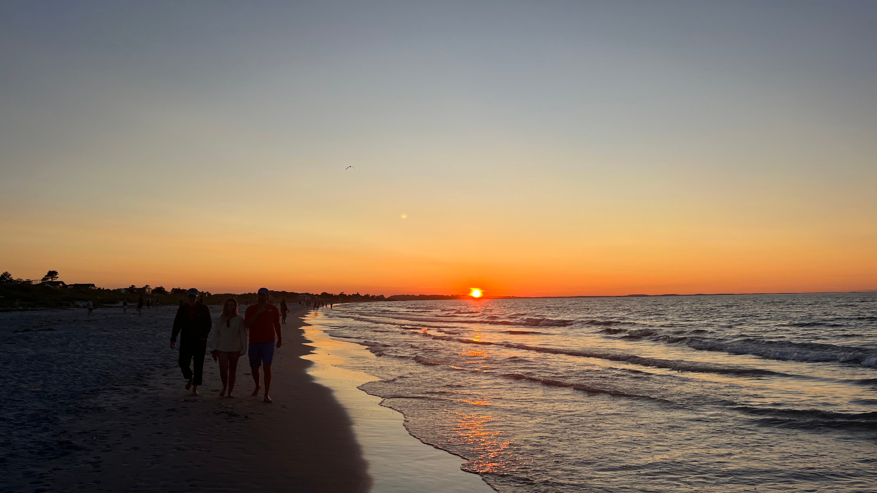 A dark silhouette of Wingaersheek Beach with a glowing orange and blue sunset horizon.