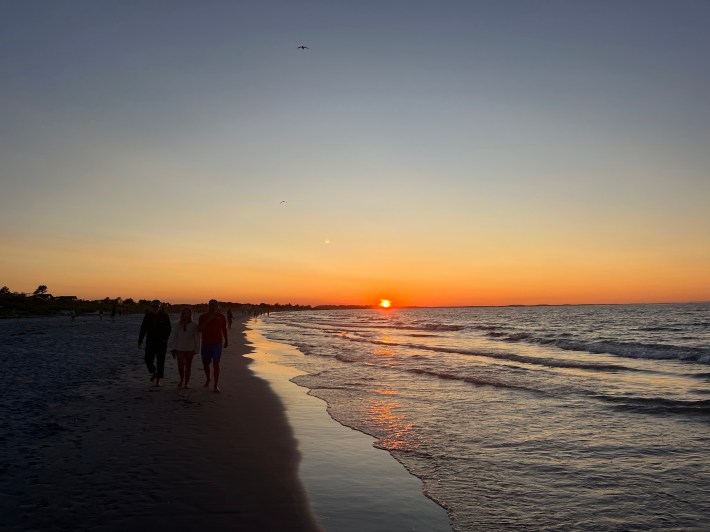 A dark silhouette of Wingaersheek Beach with a glowing orange and blue sunset horizon.